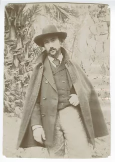 portrait photographique d’André Gide, avec moustache, barbe et chapeau, en extérieur, devant des palmiers, février-mars 1895