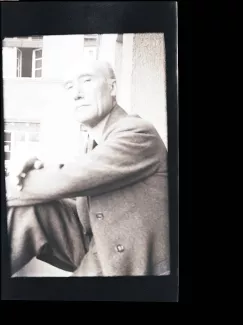 portrait photographique d'André Gide, regardant l'objectif de haut, cigarette dans la main droite, le bras gauche posé sur le genou droit, juillet 1931