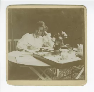 photographie de Maria Van Rysselberghe, assise à une table, écrivant