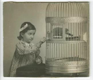 portrait photographique en buste d'Andrée Mayrisch enfant, près d’une cage d’oiseau