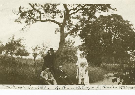 Photographie d’André Gide, avec chapeau et cape, debout, Joseph Conrad, assis à gauche, sa femme Jessie Conrad et son fils John Conrad à droite, et Valery Larbaud, assis au milieu, lors du séjour de Gide dans la propriété de Conrad, juillet 1911.
