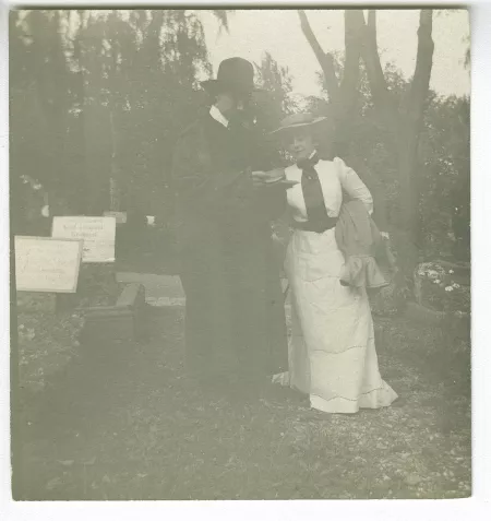 photographie d’André Gide, avec moustache et chapeau, lisant, et Maria Van Rysselberghe, en blanc, dans un cimetière, août 1903