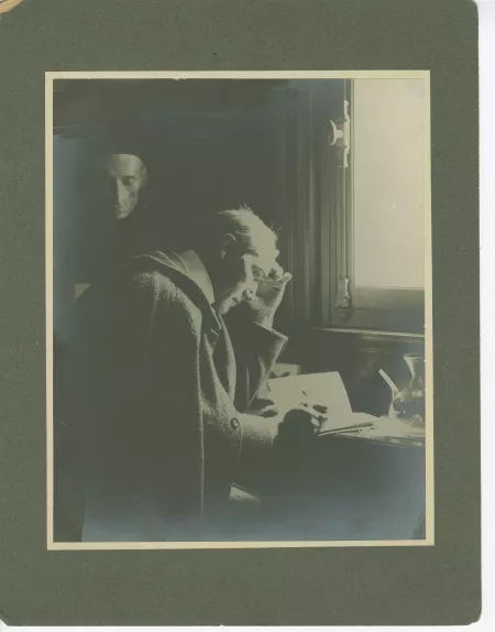 portrait photographique d’André Gide, assis à son bureau de la villa Montmorency, écrivant, sous le masque mortuaire de Leopardi, mai 1910, collé sur carton gris