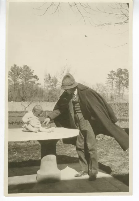 photographie d’André Gide et Catherine Gide bébé, assise sur une table en extérieur, à la Bastide Franco, mars 1924