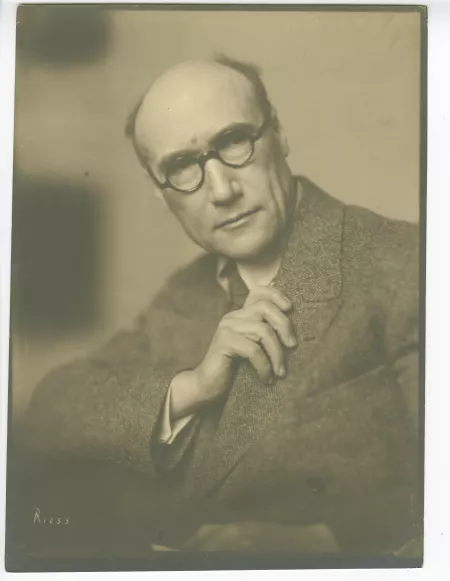 portrait photographique d’André Gide, avec lunettes, de face et la main droite sur le revers de son costume