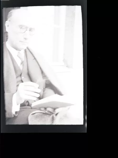 portrait photographique d'André Gide, avec lunettes, lisant, cigarette dans la main droite, juillet 1931