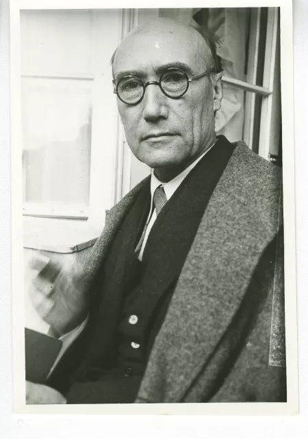 portrait photographique en buste d'André Gide, regardant l'objectif, avec lunettes, main droite floue, juillet 1931