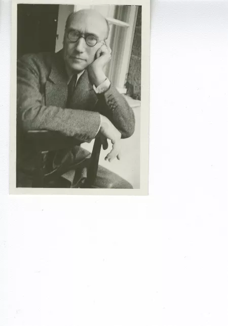 portrait photographique d'André Gide, avec lunettes, la main gauche sur la joue, à califourchon sur une chaise, juilet 1931