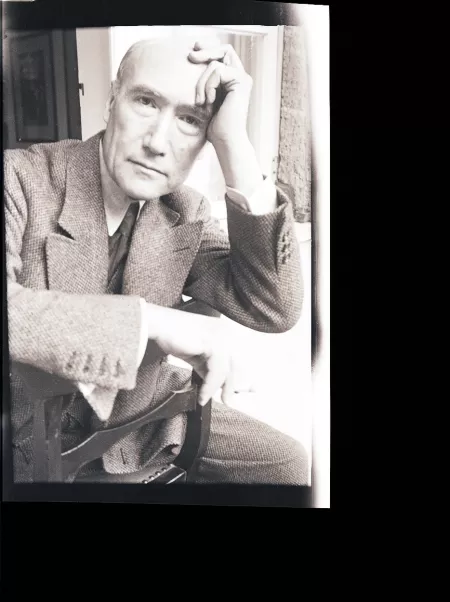 portrait photographique en buste d'André Gide, de face, regardant l'objectif, cigarette dans la main droite, la main gauche sur le front, à califourchon sur une chaise, juillet 1931