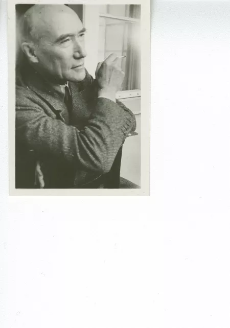 portrait photographique en buste d'André Gide, de ¾ droite, regardant devant lui, cigarette dans la main droite, à califourchon sur une chaise, juillet 1931