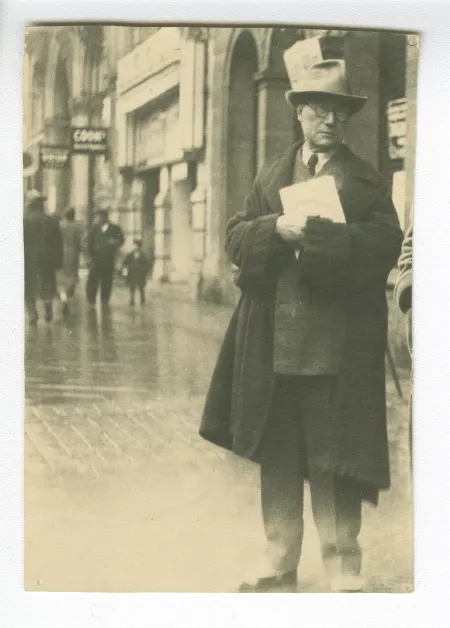 photographie d’André Gide, avec chapeau et lunettes, debout dans la rue, tenant des feuillets, octobre 1932