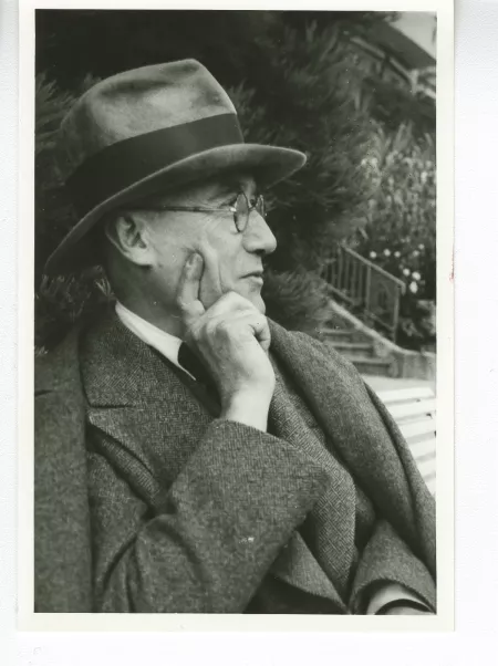 portrait photographique en buste d'André Gide, avec lunettes et chapeau, de profil droit, la main droite soutenant son menton, août 1934