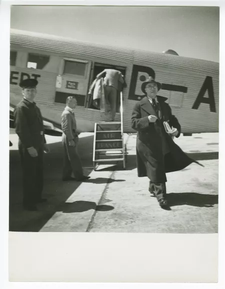 photographie d’André Gide, avec lunettes et chapeau, sortant d'un avion, en escale à Berlin lors du voyage Paris-Moscou, juin 1936