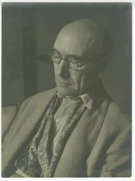 portrait photographique en buste d’André Gide, avec lunettes et foulard fleuri, de ¾ à gauche, lisant, au Vaneau