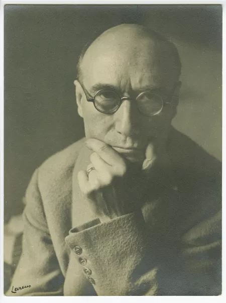 portrait photographique en buste d’André Gide, avec lunettes, de face, regardant l’objectif, la main gauche sur le menton, au Vaneau