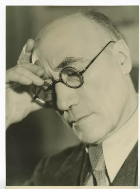 portrait photographique en gros plan d’André Gide, avec lunettes, la main droite sur le front