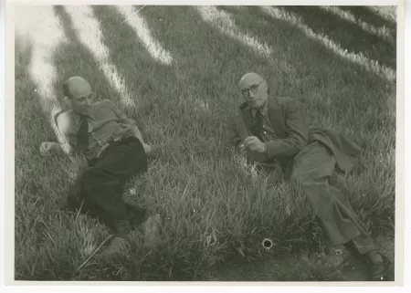 photographie d’André Gide, avec lunettes, fumant, et Jean Denoël, tout deux allongés dans l’herbe