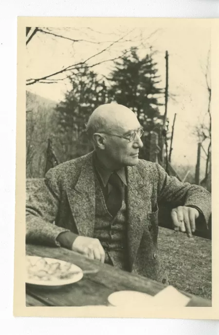 portrait photographique d’André Gide, avec lunettes, attablé, tourné vers le paysage, en extérieur, avril 1947