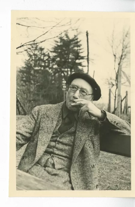 portrait photographique d’André Gide, avec lunettes et béret, fumant, en extérieur, avril 1947