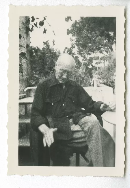 photographie d’André Gide, avec lunettes, assis sur une terrasse d'immeuble, après sa sortie de la clinique du Belvédère à Nice, été 1949