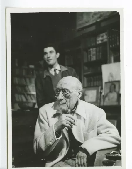 photographie d’André Gide, avec lunettes, accoudé, et l'assistant-réalisateur Jacques Nahum [?], au Vaneau ; photographie de plateau du film La vie commence demain de Nicole Védrès