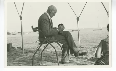 photographie d’André Gide, avec lunettes, lisant sur une plage, juillet 1950