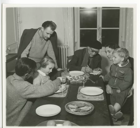 photographie montrant, de gauche à droite, Marc Allégret, Isabelle Lambert, Jean Lambert, André Gide, avec lunettes et béret, Catherine Gide et Nicolas Lambert, attablés pour le dîner, à La Mivoie, lors du tournage du film Avec André Gide de Marc Allégret