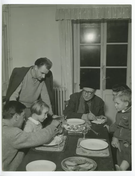 photographie montrant, de gauche à droite, Marc Allégret, Isabelle Lambert, Jean Lambert, André Gide, avec lunettes et béret, Catherine Gide et Nicolas Lambert, attablés pour le dîner, à La Mivoie, lors du tournage du film Avec André Gide de Marc Allégret