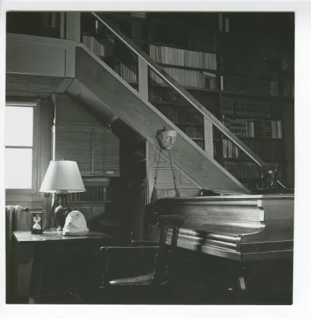 photographie montrant le bureau d'André Gide, sur lequel sont posés son masque mortuaire et son sablier, le piano d'André Gide, et, accroché à l'escalier, le masque mortuaire de Leopardi, au Vaneau