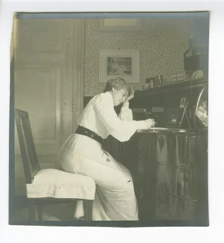 photographie de Maria Van Rysselberghe, assise à un secrétaire, écrivant, dans la maison de la rue Laugier
