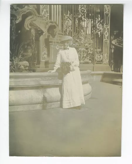 photographie de Maria Van Rysselberghe, un bouquet à la main, debout près d’une fontaine de la place Stanislas