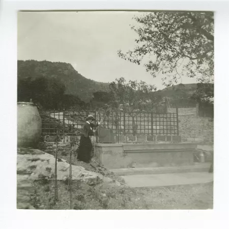 photographie de Maria Van Rysselberghe, debout près du puits, dans le jardin de la villa de Saint-Clair