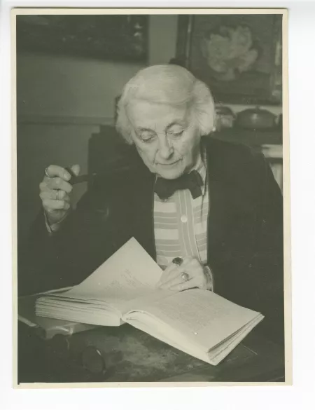 portrait photographique de Maria Van Rysselberghe, lisant, pipe en main, dans son appartement de la rue Vaneau, mai 1948