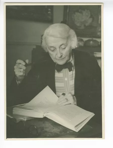portrait photographique de Maria Van Rysselberghe, lisant, pipe en main, dans son appartement de la rue Vaneau, mai 1948