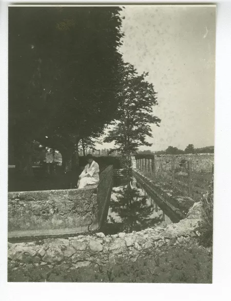 photographie de Maria Van Rysselberghe, assise sur un muret au-dessus d’un canal, à la Bastide Franco