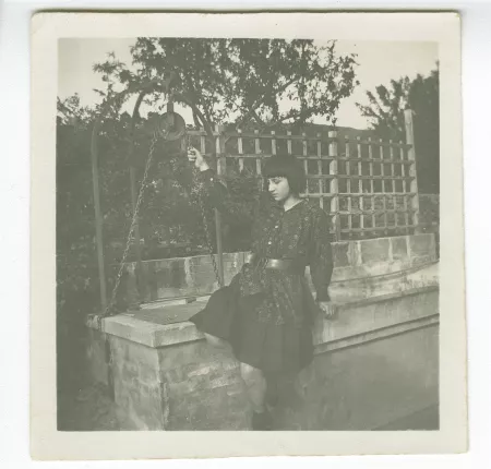 photographie d'Andrée Mayrisch enfant, aux cheveux longs, assise près du puits dans le jardin de la villa de Saint-Clair