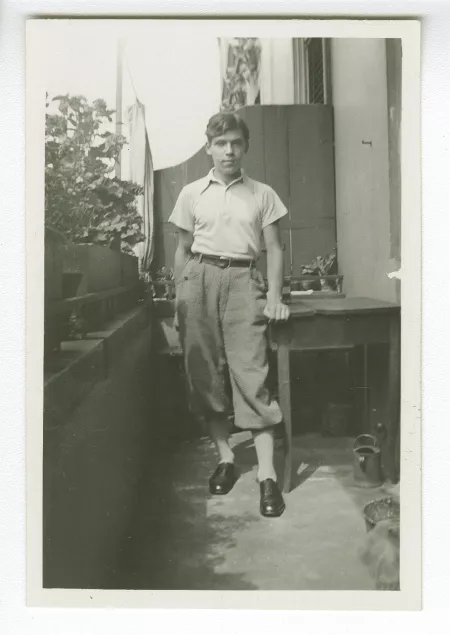 photographie d’un jeune homme, appuyé à une table sur un balcon