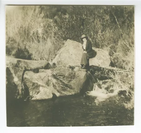 photographie d'une femme non identifiée, assise au bord d'une rivière