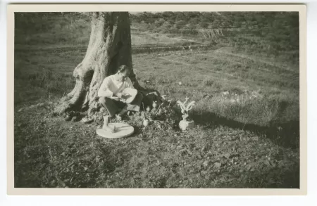 photographie d’un homme, assis dans l’herbe, avec des sculptures autour de lui