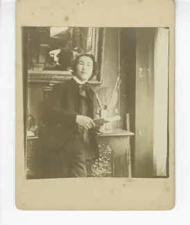 portrait photographique d’André Gide, accoudé à un buffet, tenant un livre