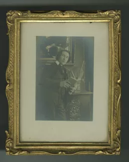 portrait photographique d’André Gide, accoudé à la cheminée, bouche entrouverte, tenant un livre
