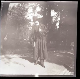 photographie d'André Gide, avec moustache et chapeau, tenant un livre, dans un cimetière, août 1903