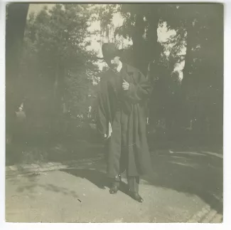 photographie d'André Gide, avec moustache et chapeau, tenant un livre, dans un cimetière, août 1903