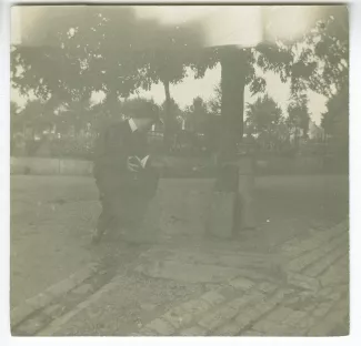 photographie d’André Gide, avec moustache et chapeau, tenant un livre, assis près d’un point d’eau, août 1903