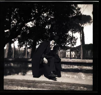 photographie d'André Gide, avec chapeau et cape, assis sur une margelle, lors du voyage des Van Rysselberghe en Italie, mars-avril 1909