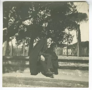 photographie d'André Gide, avec chapeau et cape, assis sur une margelle, lors du voyage des Van Rysselberghe en Italie, mars-avril 1909