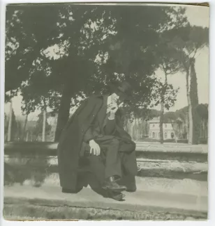 photographie d'André Gide, avec chapeau et cape, assis sur une margelle, lors du voyage des Van Rysselberghe en Italie, mars-avril 1909