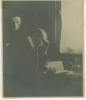 portrait photographique d’André Gide, assis à son bureau de la villa Montmorency, écrivant, sous le masque mortuaire de Leopardi, mai 1910