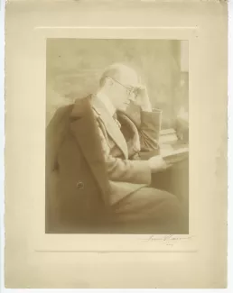 portrait photographique d’André Gide, assis, de profil, lisant à un bureau