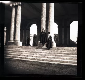 photographie d'André Gide, avec chapeau et cape, et Élisabeth Van Rysselberghe, enceinte de Catherine Gide, debout sur l’escalier d’un monument à Rapallo, janvier-février 1923